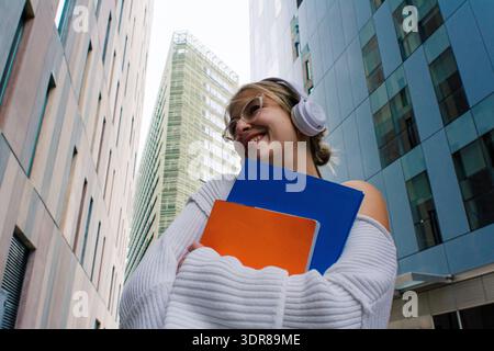 Happy young woman student walking campus with books Stock Photo