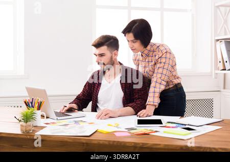 Two People Collaborating on a Laptop in a Bright Office Space During the Day Stock Photo