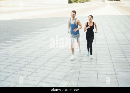 Two People Running Together on a City Sidewalk During Daylight in a Busy Urban Area Stock Photo