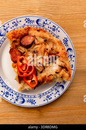 A vertical photograph of a wooden table topped with freshly baked focaccia with sausage and onions, perfect for rustic food concepts. Stock Photo