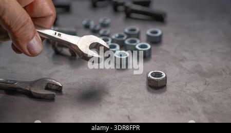 Mechanic hand holding socket wrench on steel work bench Stock Photo