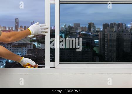 Construction worker repairing the sliding window on condominium room. Stock Photo