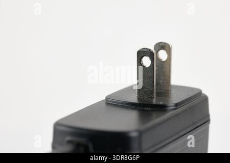 Macro shot of a black AC power adapter with two-prong Type A plug on a white background Stock Photo