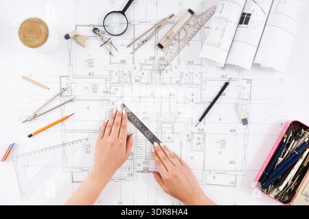 Hands Working on Architectural Plans With Various Tools and Materials on the Table Stock Photo