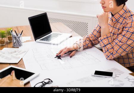 Architect Studies Building Plans on Desk With Laptop and Tools in Modern Workspace Stock Photo