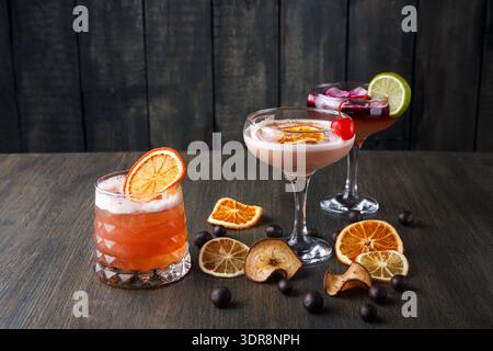 Three Colorful Cocktails Displayed on a Wooden Table With Dried Fruit Garnishes Stock Photo