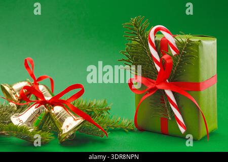 Gift Wrapped With Red Ribbon and Two Bells on Green Background During Holiday Season Stock Photo