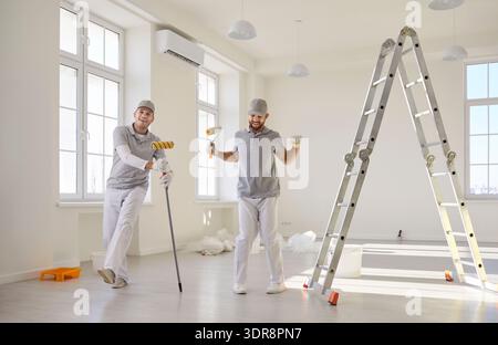 Professional painters with rollers and ladder in bright room interior renovation Stock Photo