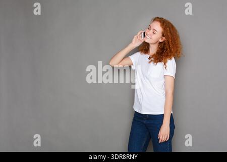 Young Woman Talking on the Phone With a Smile in a Simple Setting Stock Photo