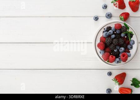 Berry Collection on White Wooden Table With Fresh Fruits Arranged in a Bowl and Scattered Nearby Stock Photo