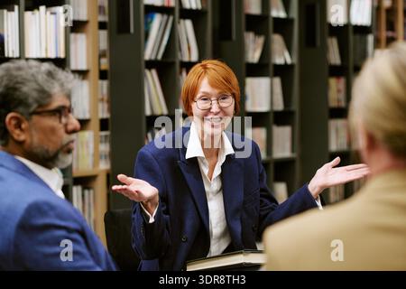 Middle Aged Caucasian Woman Presenting Ideas during Book Discussion Meeting Stock Photo