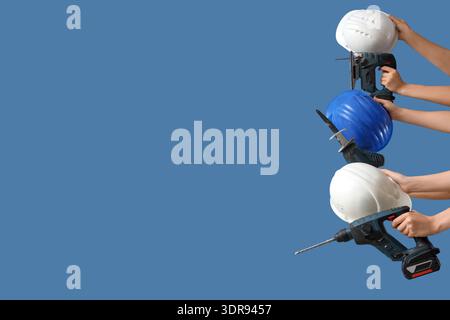Hands with hardhats and construction tools on blue background Stock Photo