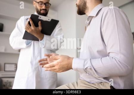 Closeup sick male share complaints with medical worker taking notes Stock Photo
