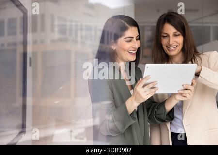 Two positive businesswomen using digital tablet together in office Stock Photo