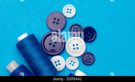 Sewing supplies arranged on a blue background with thread and buttons of different colors Stock Photo
