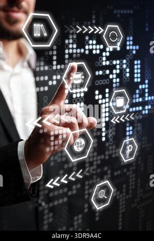 Man interacts with digital interface showing various icons and data patterns in a tech setting Stock Photo