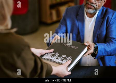 Middle Aged Male Author Handing Book to Middle Aged Woman Stock Photo