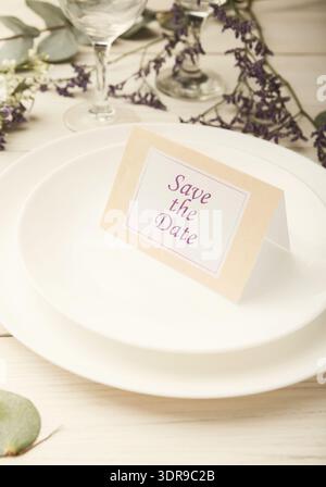 Invitation Card for Event Displayed on White Plates With Flowers Beside It in Soft Lighting Stock Photo