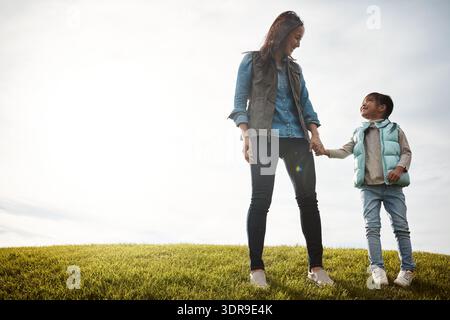 Asian, mother and holding hands with child outdoor for love, affection and bonding together. Below, woman or happy with kid for family getaway Stock Photo