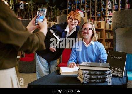 Caucasian Middle Aged Man Signing Book with Caucasian Middle Aged Woman Posing Stock Photo