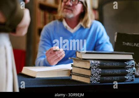Middle Aged Caucasian Man Signing Books during Presentation Event Indoors Stock Photo