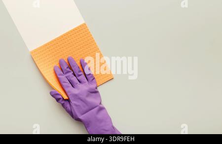 Cleaning Activity With a Purple Glove and Sponge on a Light Surface Stock Photo