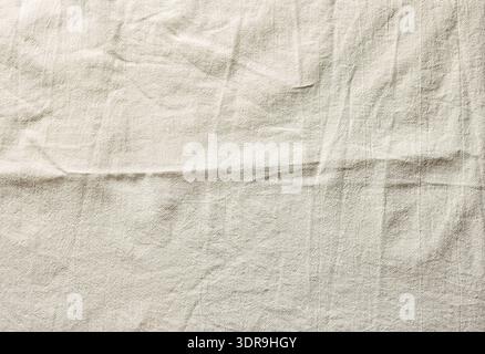 Close-up of wrinkled cotton fabric texture in soft beige tone. Natural textile surface with visible creases suitable for background, fashion, minimal Stock Photo