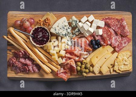 set of various meat and cheese snacks on wooden cutting board, closeup of delicatessen served for party Stock Photo