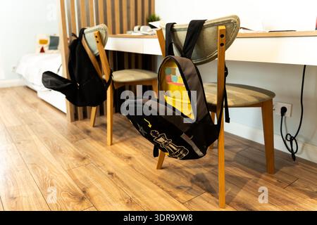 A schoolchildren's room with a desk stocked with books for homework and backpacks hanging on the backs of chairs in a cozy apartment. Organized study Stock Photo