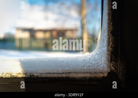 Frost on the inside of a window in winter, showing a frozen house with delicate ice crystals covering the glass. Beautiful yet concerning natural patt Stock Photo