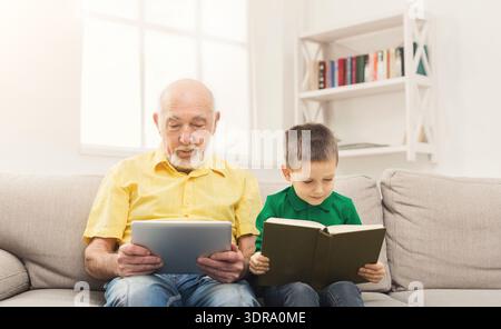 Grandfather and Grandson Reading Books Together in Living Room During Daytime Stock Photo