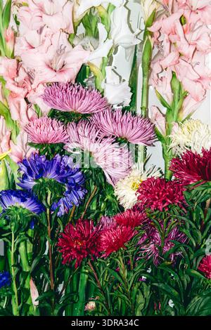 Close up of pink gladiolus and colorful aster flowers in dense bouquet. Sustainable gardening, local blooms, slow flower movement, seasonal farming. Stock Photo
