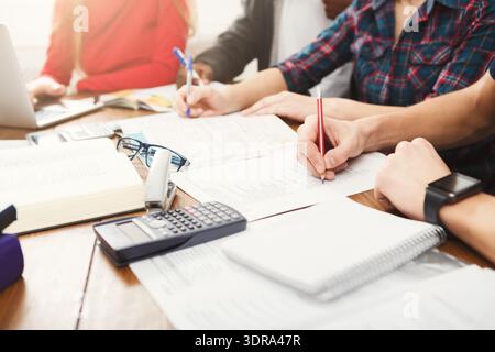Group of Students Working Together on Assignments at a Table During Study Session in a School Stock Photo