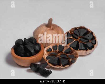 Two whole bulbs of black fermented garlic and one cut Stock Photo