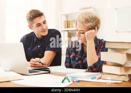 Two Students Work Together on a Project in a Study Space With Books and a Laptop Stock Photo