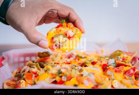 Close up of hand of taking nachos on isolated background. Hand taking and showing a nacho isolated Stock Photo