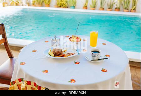 Traditional breakfast served at the table near a swimming pool. Breakfast served on the table with a swimming pool in the backgr Stock Photo