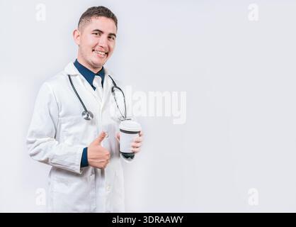 Satisfied doctor holding takeaway coffee isolated. Young doctor holding a coffee to go isolated. Smiling doctor holding coffee w Stock Photo