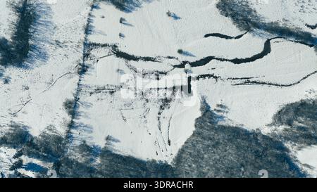 Aerial top view of winding river flowing through snow covered winter landscape Stock Photo