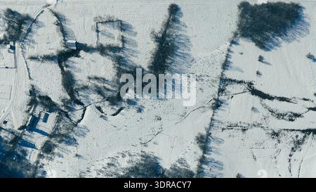 Overhead drone shot of winding river creating abstract patterns across snow covered terrain Stock Photo