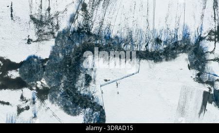 Meandering winter river cutting through snow covered landscape in aerial perspective Stock Photo