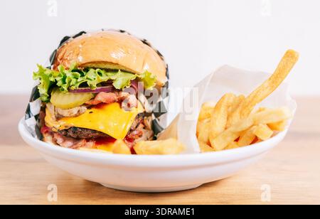 Cheeseburger with fries on wooden table. Close up of a delicious hamburger with french fries on wooden table with copy space Stock Photo