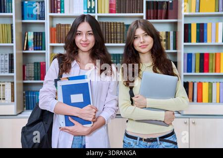 Portrait of two teenage students classmates looking at camera in classroom library Stock Photo
