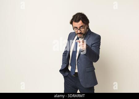 A Man Wearing a Suit and Glasses Stands in a Studio Stock Photo