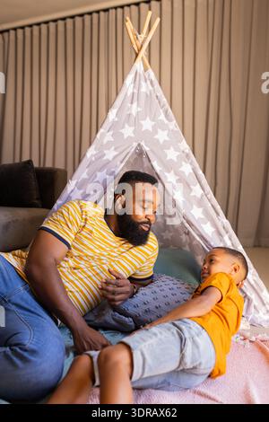Playing in tent, father and son bonding and smiling in living room, copy space, in teepee Stock Photo