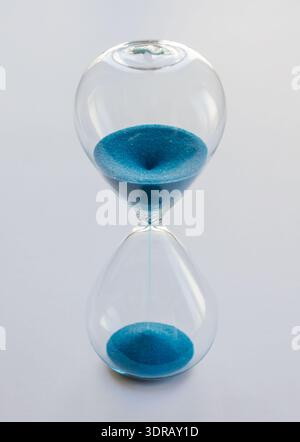 Hourglass containing blue sand isolated on white background Stock Photo