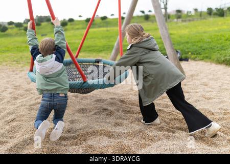 Children playing on nest swing in park Stock Photo
