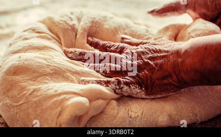 Hands making dough for pizza. Preparation doughs women's hands. Making dough by male hands at bakery Stock Photo