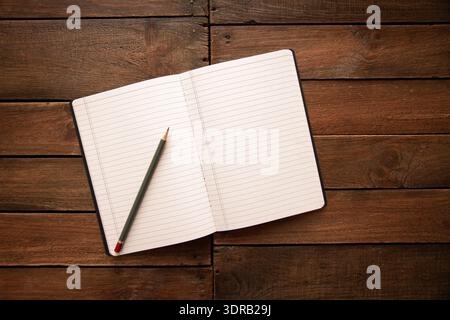 Open notebook and pencil on a rustic wooden board Stock Photo