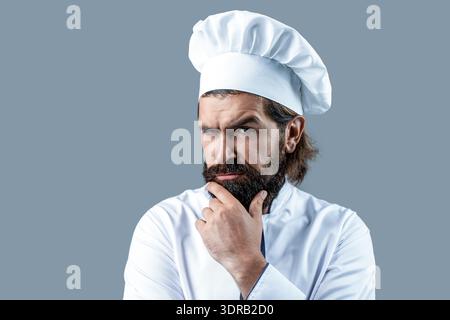 Portrait of a serious chef cook. Bearded chef, cooks or baker. Bearded male chefs isolated. Cook hat. Confident bearded male chef in white uniform Stock Photo
